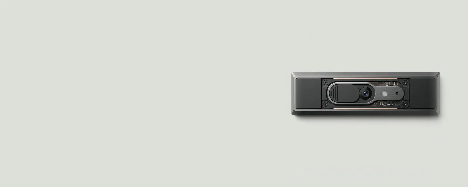 Studio render of the top bezel of a laptop lid with a small camera lens and a sliding privacy shutter half closed beside a tiny indicator