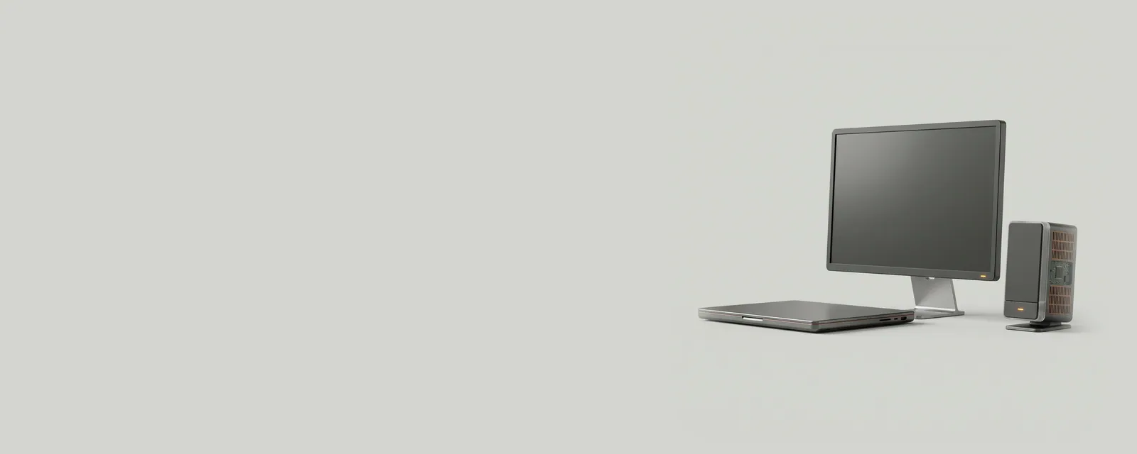 Studio render of a closed laptop beside a monitor and a speaker, all with dim amber standby indicators under low, even light