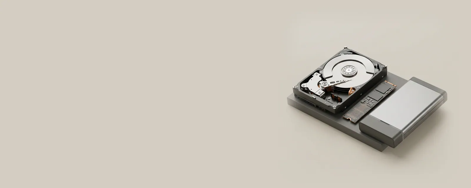 Studio render of an M.2 SSD, a 3.5-inch hard drive with its top cover removed and an aluminium external enclosure arranged on a graphite plinth